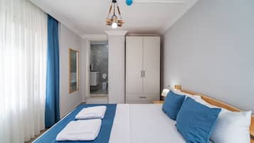Habitació d'hotel amb un llit, un mirall, un armari i un bany visible per una porta oberta.