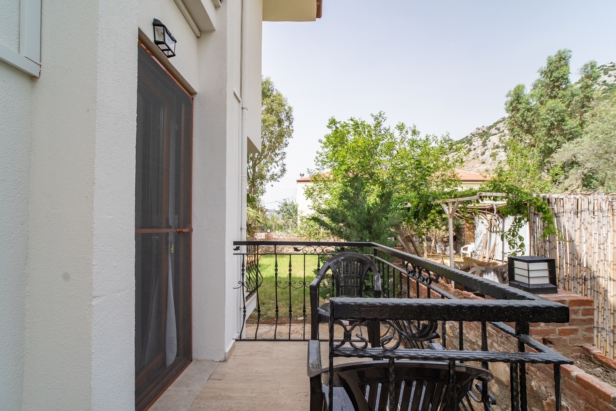 A balcony with a metal railing, a wooden chair, and a table.