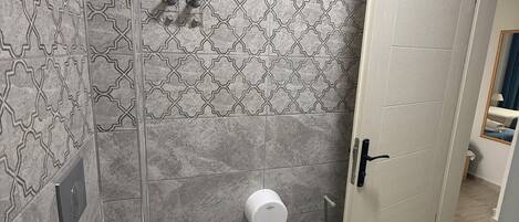 A bathroom with a toilet, a hand dryer, and a door.