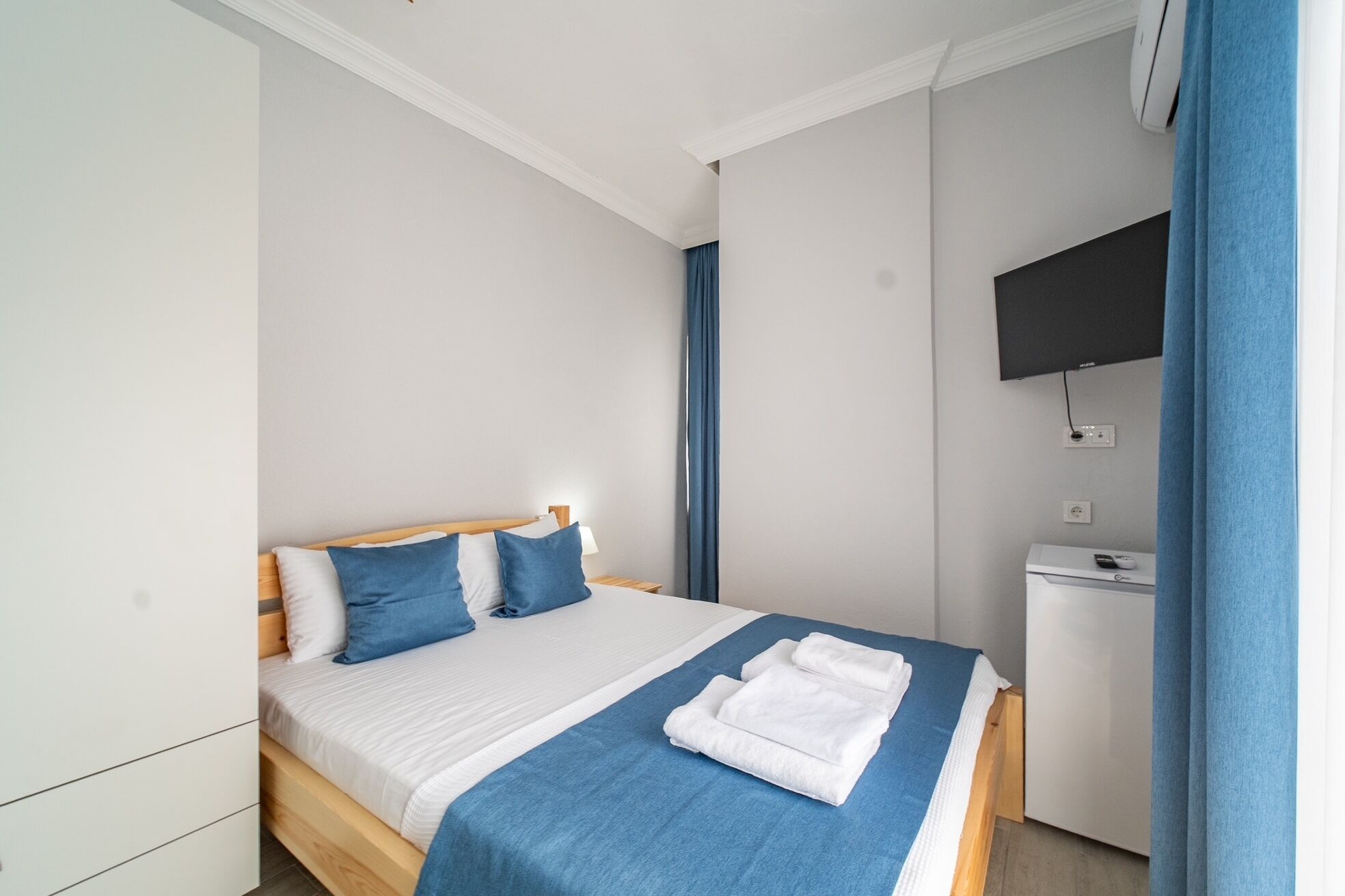 A bedroom with a bed, a TV, and a small desk.