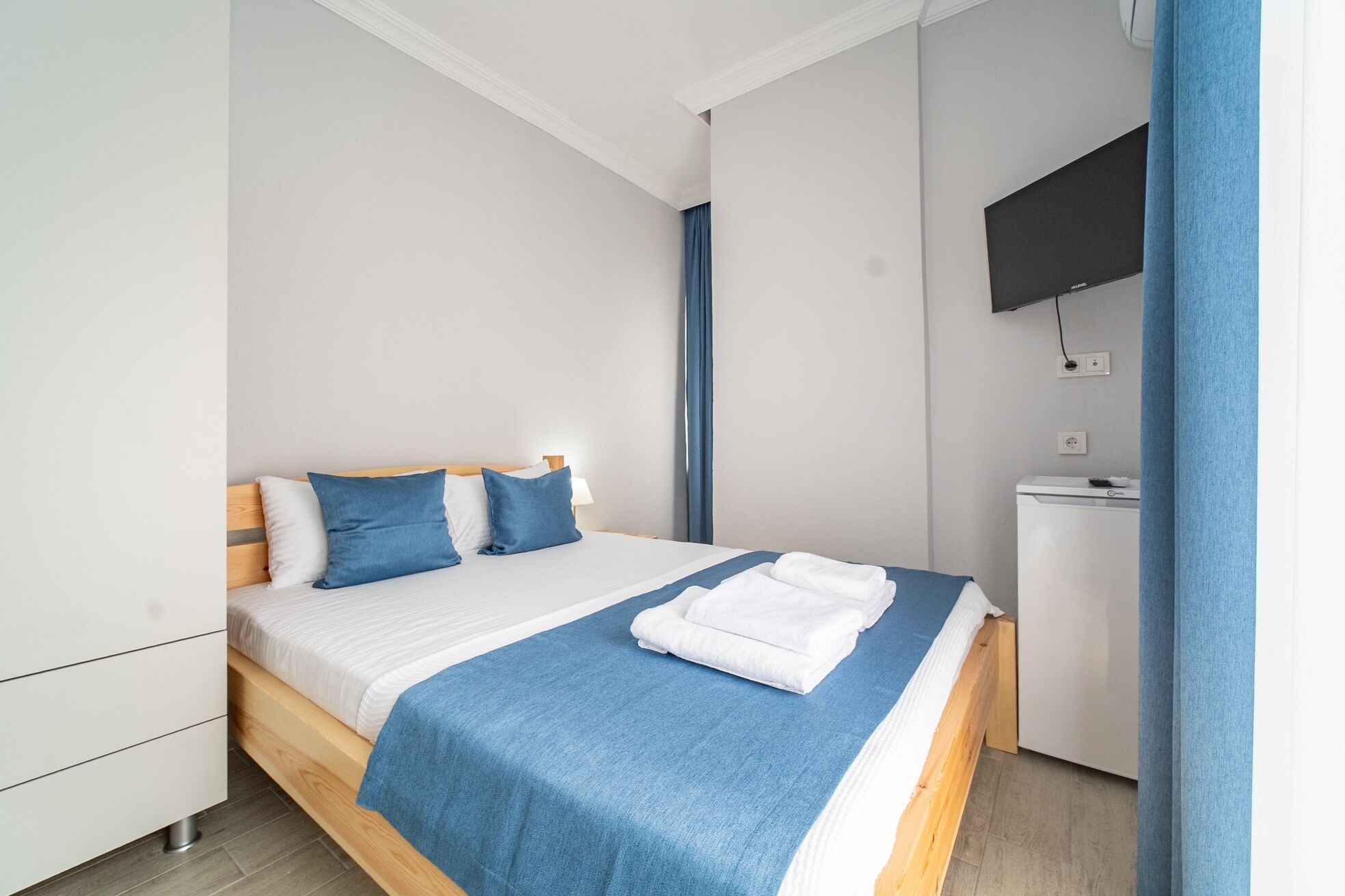 A modern bedroom with a bed, a flat-screen TV, and a small desk.
