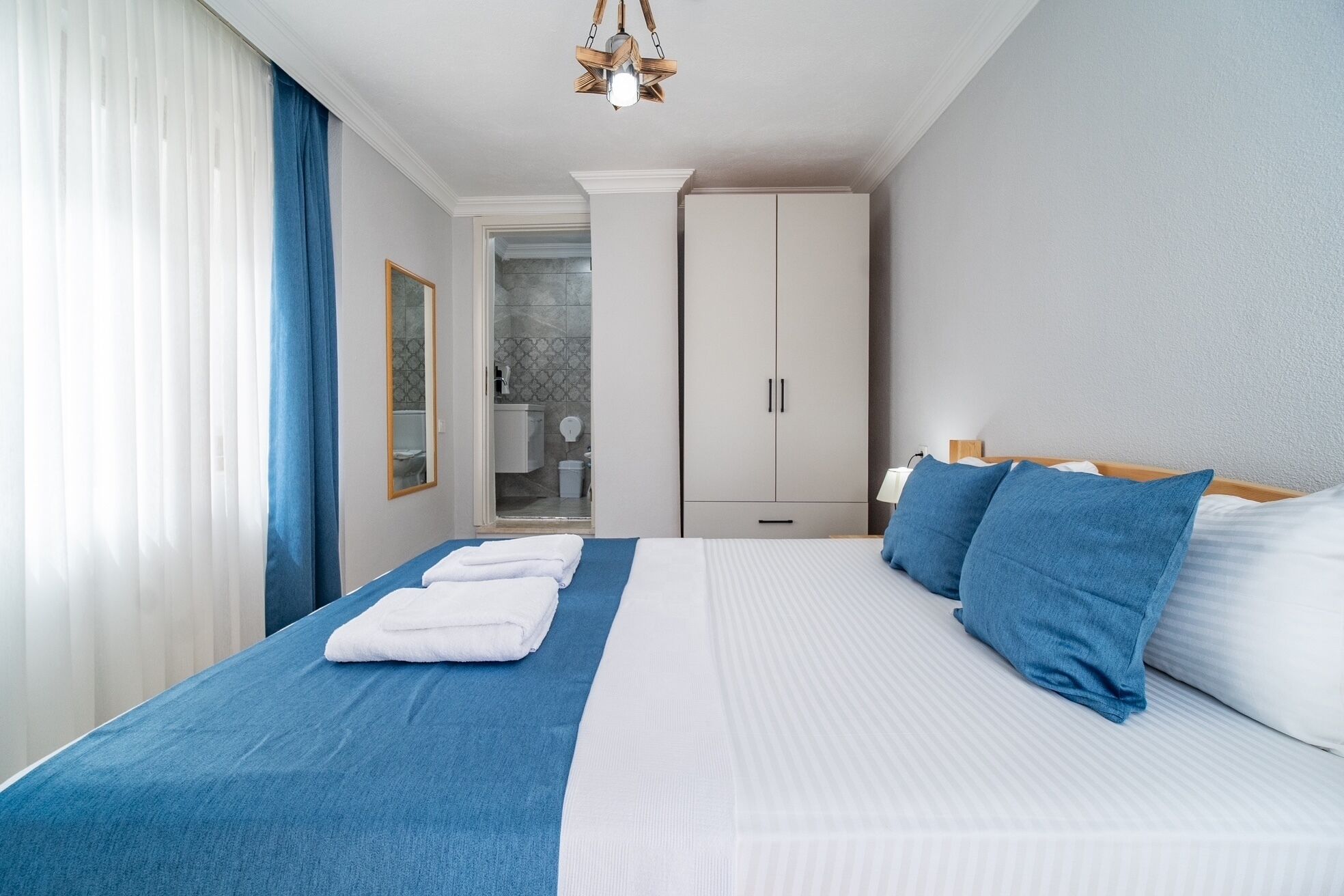 A hotel room with a bed, a wardrobe, a bathroom, and a shower area.