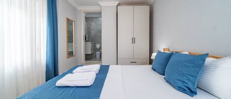 A hotel room with a bed, a wardrobe, a bathroom, and a shower area.