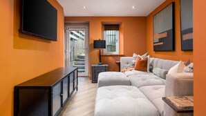 Un salon moderne avec un canapé d’angle, un téléviseur à écran plat et des œuvres d’art accrochées aux murs.