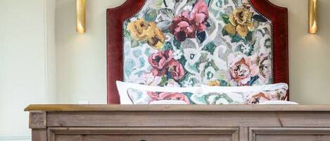 A wooden dresser with multiple drawers and a floral headboard.