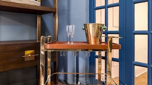 A wooden cart with a metal frame, a bucket, and two glasses on a wooden floor.
