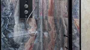 Una ducha con pared de mármol y marco negro.