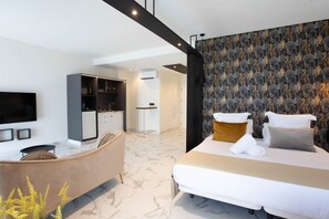 Une chambre d’hôtel moderne équipée d’un lit, d’un canapé, d’une télévision et d’une kitchenette.