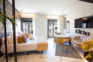 Une chambre d’hôtel moderne équipée d’un lit, d’un coin salon, d’une table ronde et d’un téléviseur.