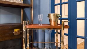 A wooden cart with a metal frame, a bucket, and two glasses on a wooden floor.
