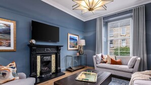 A living room with a fireplace, a sofa set, a coffee table, and a television mounted on the wall.