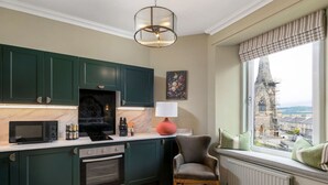 Een moderne keuken met donkergroene kastjes, een zwarte magnetron en een rode lamp.