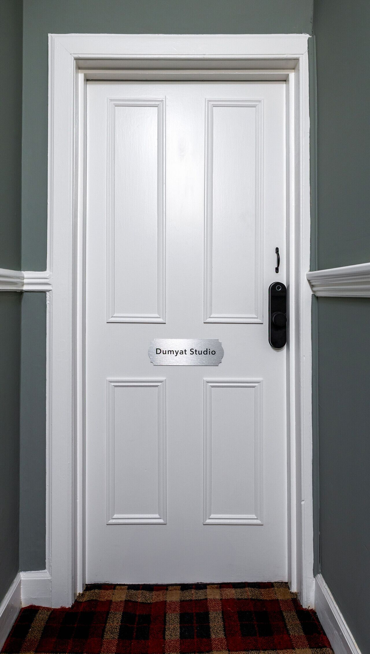 A white door with a nameplate reading "Dumyat Studio" and a doorbell.