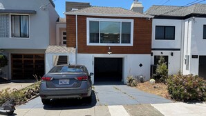 A modern two-story house with a garage, a parked car, and a well-maintained front yard. - Cozy 2-Bedroom Guesthouse with Private Patio (San Francisco)