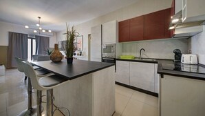Una cocina moderna con una isla central, electrodomésticos de acero inoxidable y una zona de comedor con taburetes de bar.