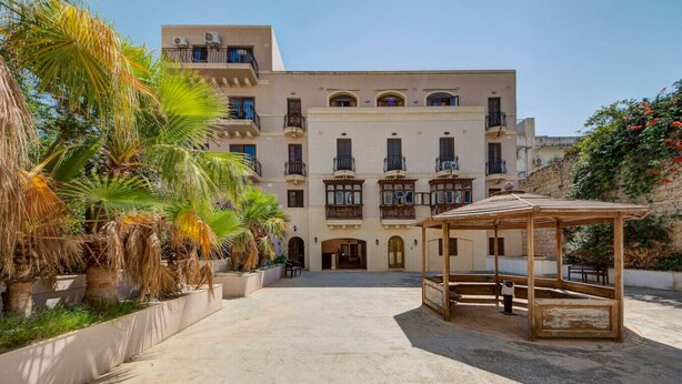 Un edificio con patio central, varios balcones y una pérgola de madera.