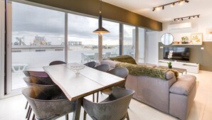 Una sala moderna con comedor, ventanas amplias y vistas a la ciudad.