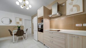 Una cocina moderna con comedor, que incluye un horno empotrado, una campana extractora de acero inoxidable y una encimera blanca.