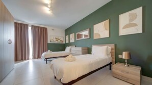 Un dormitorio moderno con dos camas, un aparador y obras de arte en las paredes.