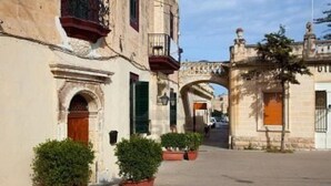 A street with historic buildings, a stone archway, and potted plants. - Stylish 1BR Apt with sofabed & backyard, Attard (Attard)
