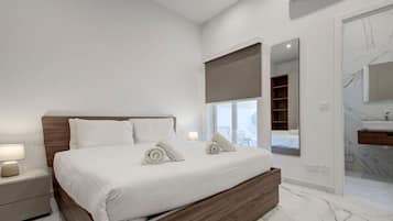 A modern bedroom with a large bed, bedside tables, a mirror, and an air conditioning unit.