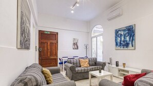 Un salon moderne avec des canapés gris, une table basse et un coin repas avec des chaises bleues.
