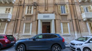 Il s’agit d’un bâtiment au style architectural classique, doté d’une entrée centrale avec une porte en bois et d’une enseigne au-dessus. De nombreuses fenêtres sont agrémentées de volets, et le bâtiment présente une façade symétrique.