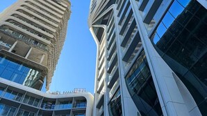 A modern high-rise building with a unique angular design, featuring multiple glass windows and a visible construction crane. - Concierge Stay at Mercury Towers pjazza ! (San Ġiljan)