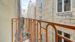 A narrow alleyway between buildings with a metal railing, a window with the number 360, and a view of the street below. - Cozy 3rd-Floor Valletta Apartment by the Seafront (Il-Belt Valletta)