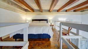 A bedroom with a large bed, wooden beams, white walls, and a wooden floor. - Unique seafront Loft overlooking Valletta`s views (Il-Belt Valletta)