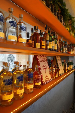 Un comptoir de bar bien garni de différentes bouteilles d’alcool, notamment de la vodka Absolut et d’autres spiritueux.