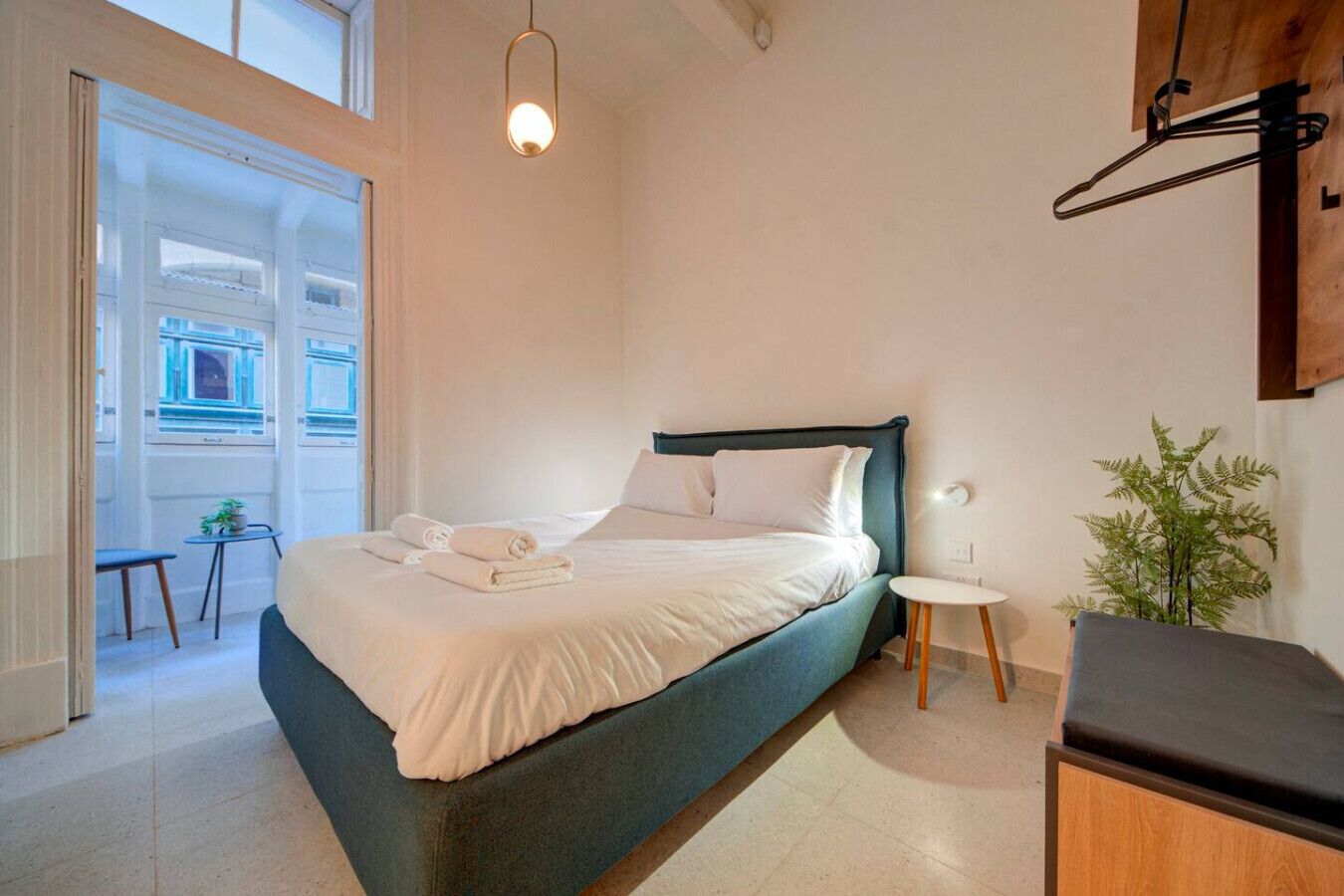 Un dormitorio con cama, mesita de noche y lámpara colgante.