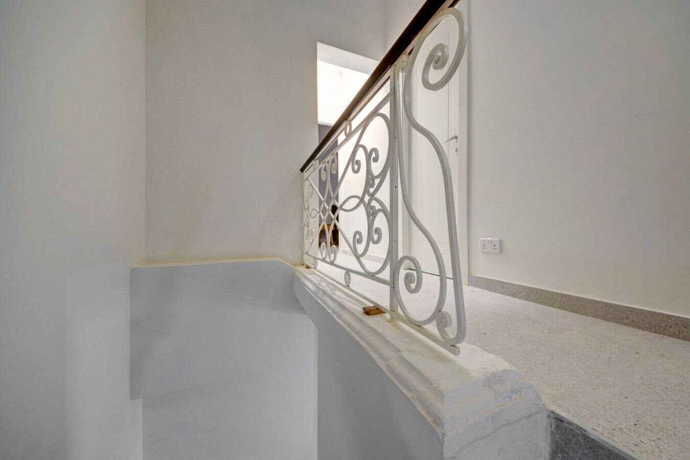 A staircase with a white railing and a plain wall.