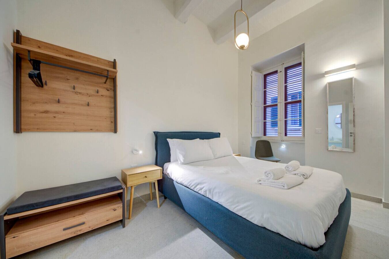 Un dormitorio con cama, mesita de noche y un banco de madera.