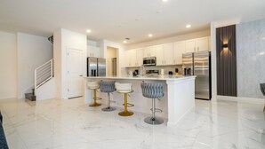 Uma cozinha moderna com armários brancos, eletrodomésticos de aço inoxidável e piso de mármore.
