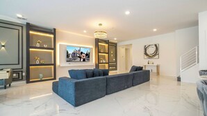 Uma sala de estar moderna com um amplo sofá de canto, um candelabro e um quadro emoldurado na parede.