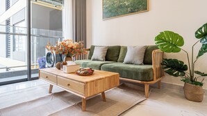 Un salón moderno con un sofá verde, una mesa de centro de madera y un ventanal con vistas a un edificio.