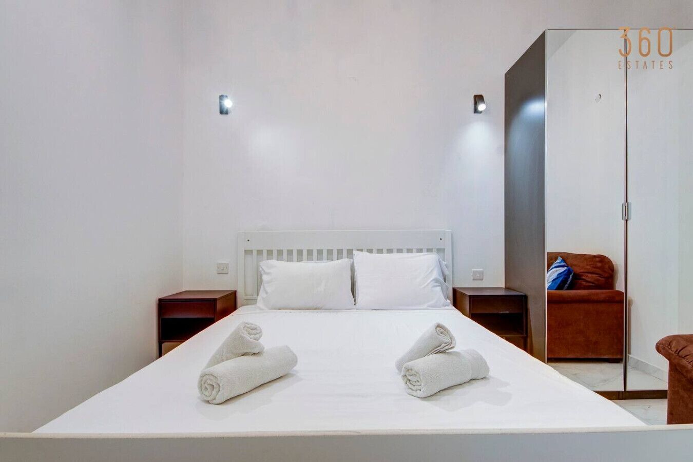Une chambre d’hôtel avec un grand lit, deux tables de chevet, une armoire et un miroir.