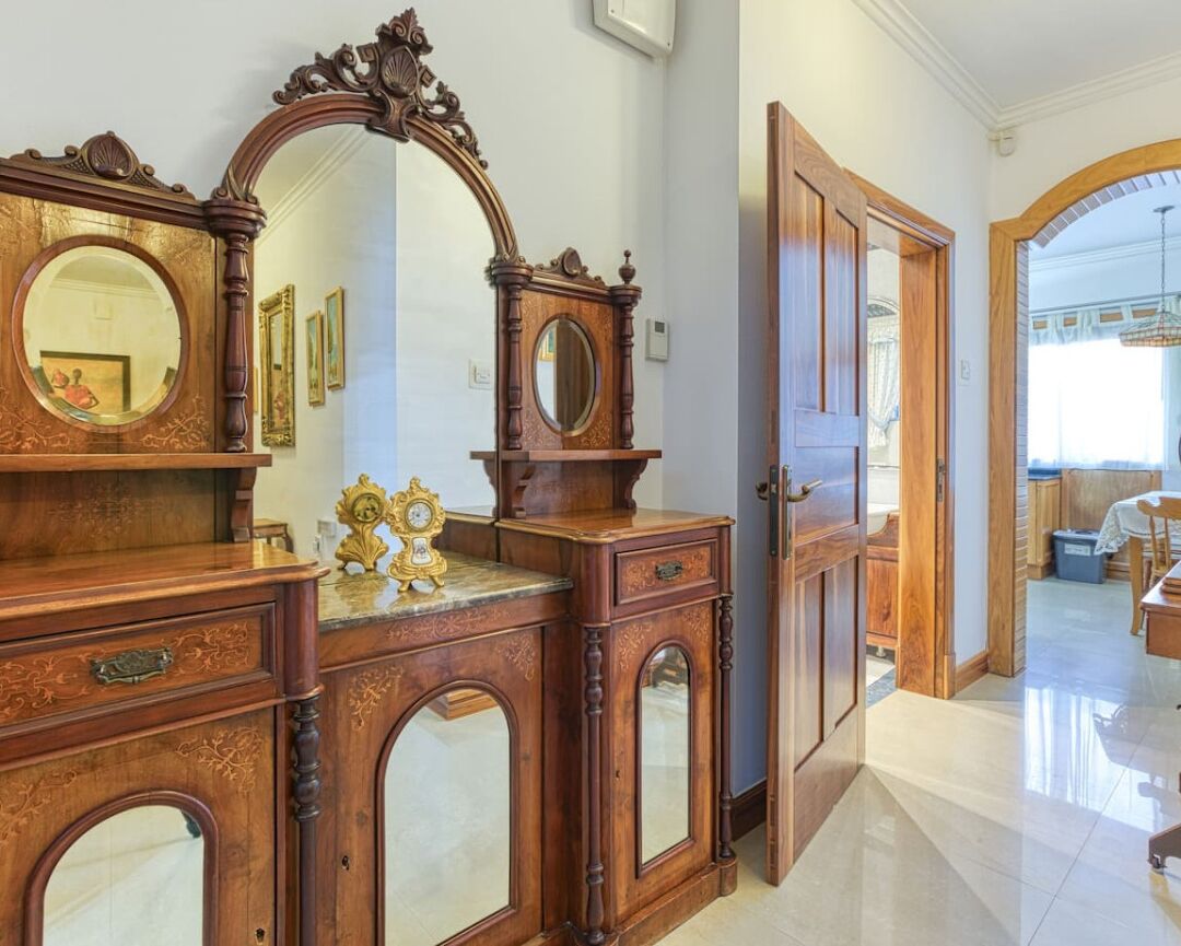 A spacious room with a large wooden dresser, a mirror, and a door leading to another area.