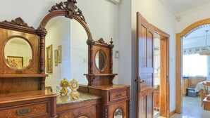 Ein geräumiges Zimmer mit einem großen Holzschrank, einem Spiegel und einer Tür zu einem weiteren Bereich.