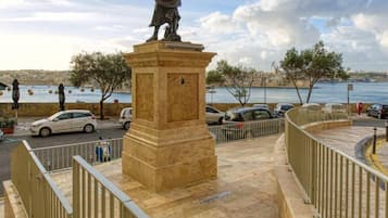 A statue on a pedestal in a public square with a waterfront view.