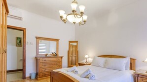 Ein Schlafzimmer mit einem hölzernen Bett, einem Schminktisch, einem Spiegel und einer Chandelier.