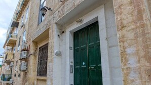 Ein Gebäude mit einer grünen Tür, einem Fenster und einer Klimaanlage an der Wand.