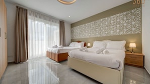 A modern hotel room with two beds, a large window with curtains, a decorative wall pattern, and a clean, tiled floor.