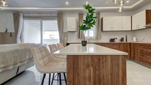 A modern kitchen with a central island, wooden cabinets, and a potted plant.