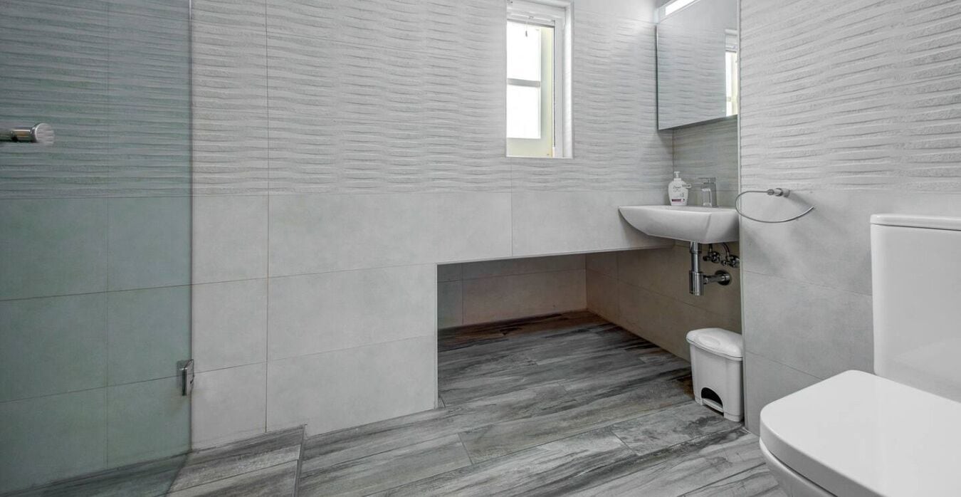 Un baño con cabina de ducha de vidrio, un lavabo blanco y un inodoro.