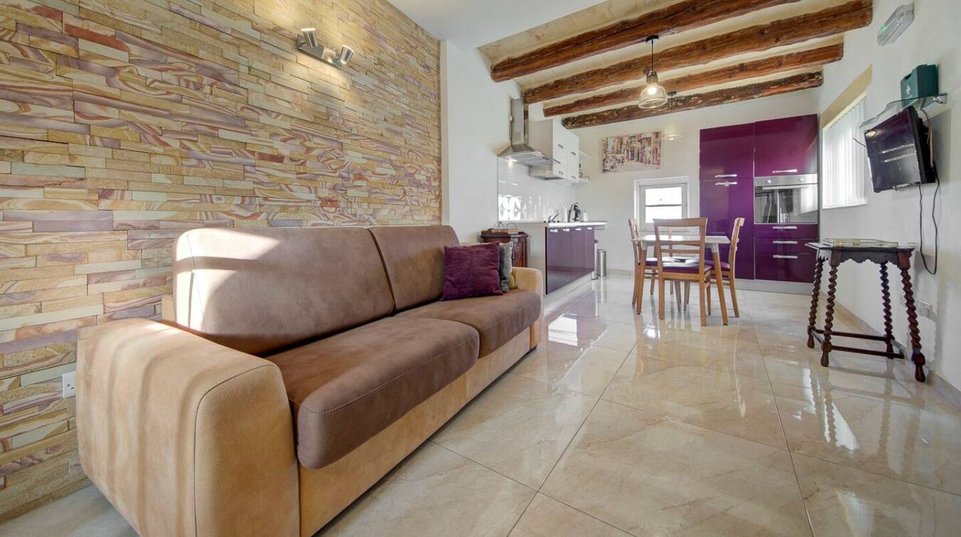 Ein modernes Wohnzimmer mit einem braunen Sofa, einem Holztisch und einer Wand mit Steinmuster.