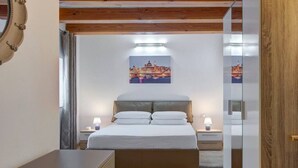 Een slaapkamer met een bed, nachtkastjes, een wanddecoratie en een houten plafond.