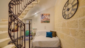 A bedroom with a bed, a clock, and a staircase with ornate railings.