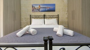A neatly made bed with a headboard, pillows, and rolled towels. - Cozy 1BR Apt in Birgu – Traditional Maltese Charm (Birgu)